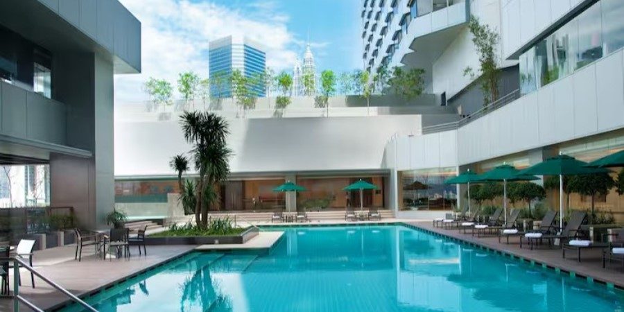 A stylish pool within a modern structure, equipped with lounge chairs and umbrellas for guests to enjoy.